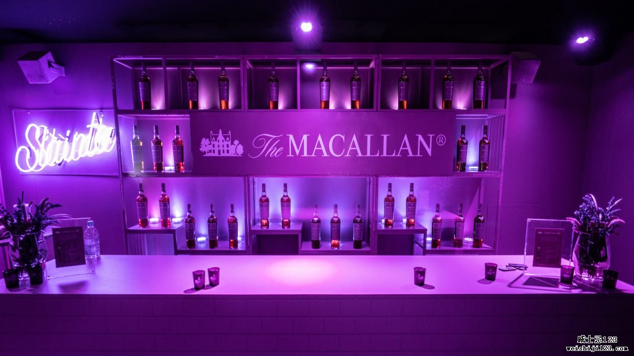 紫光沐浴着一家酒吧，背景是 The Macallan 和瓶装威士忌