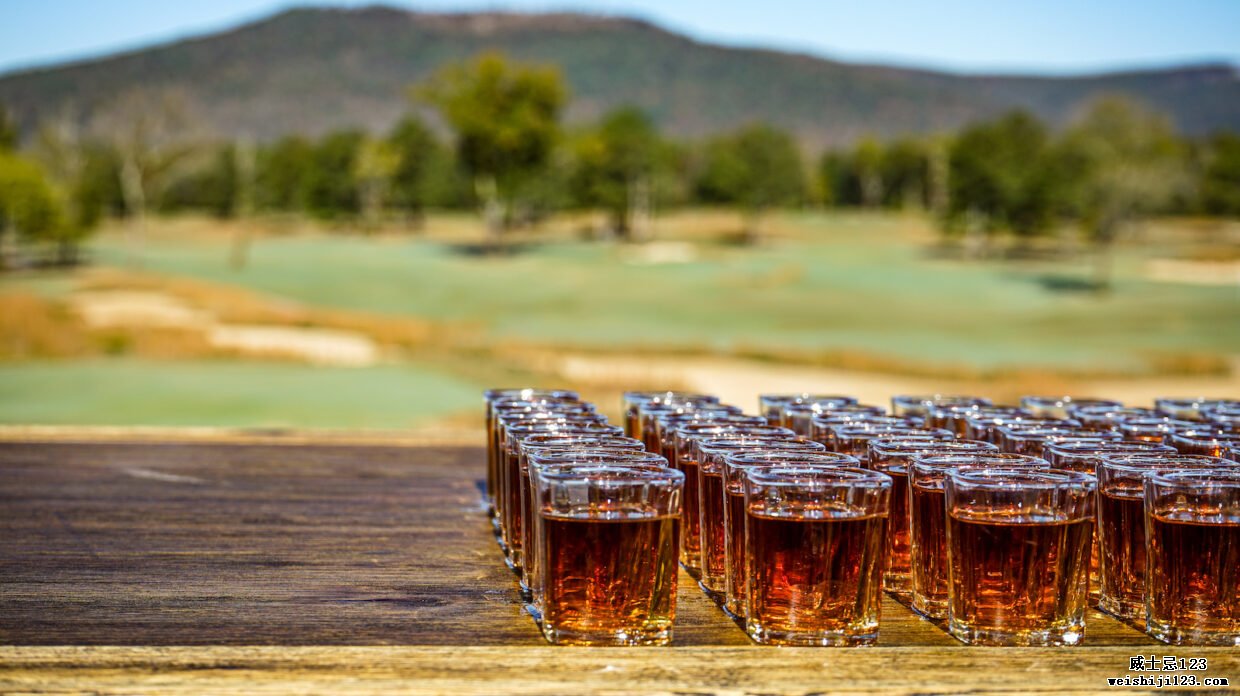 在高尔夫球场前的木桌上排列着威士忌的照片