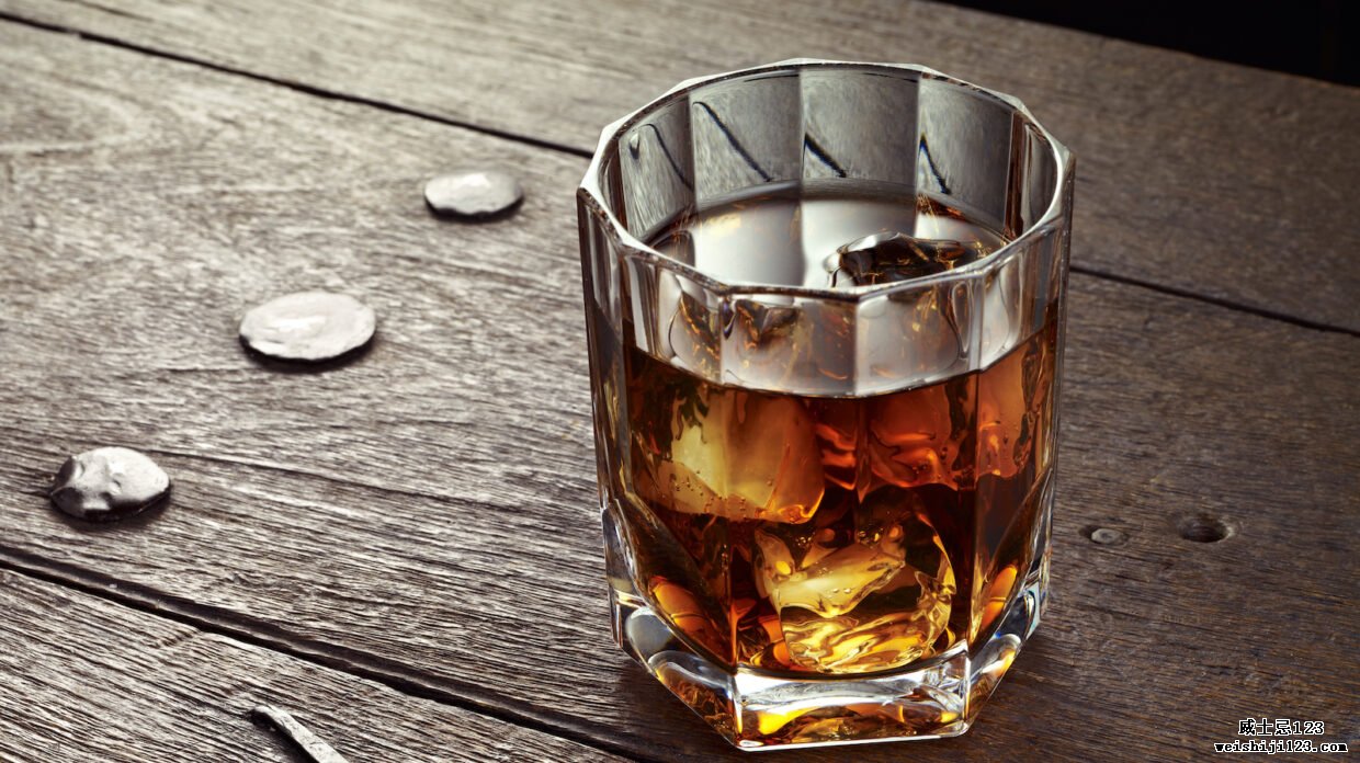 威士忌加冰在木桌上的水晶玻璃中。