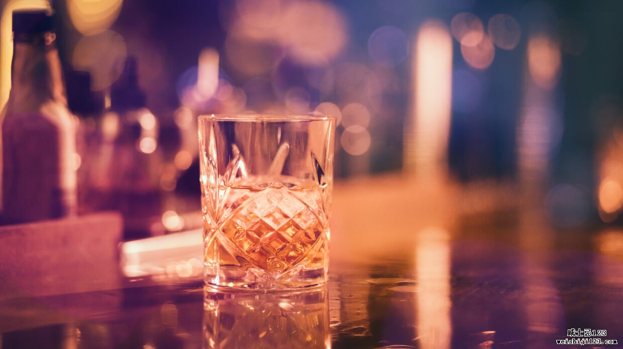 晚上在酒吧柜台上的老式玻璃杯中供应加冰的威士忌