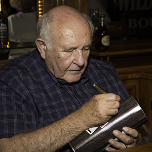 2013 年 9 月 18 日，在肯塔基州波本音乐节期间，野火鸡酿酒大师吉米·罗素在一个救赎罐上签名。照片 ©2013，Mark Gillespie。 
