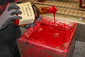 Maker's Mark Distillery 的工人用手将瓶子浸入该品牌的传统红蜡中。 档案照片 © 2008 年 Mark Gillespie。